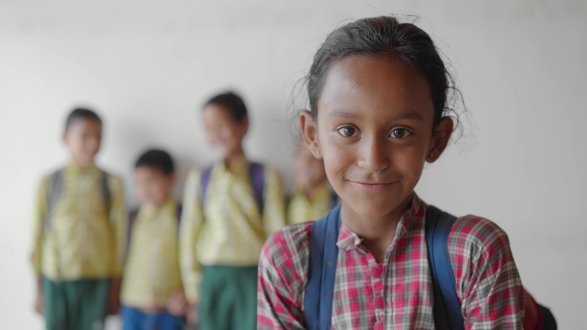 Close shot of a young little adorable primary school girl wearing a school uniform with backpack smiling joyfully staring at the camera standing in classroom learning and education concept Royalty-Free Stock Footage #1080062690