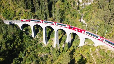 Filisur, Switzerland - October 1 2021: Dramatic aerial drone of a sightseeing luxury Glacier Express train that goes through the famous Landwasser Viaduct in Canton Graubunden in the alps. 