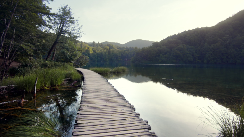 Young traveler in shorts walking on a wooden bridge near Plitvice Lake
