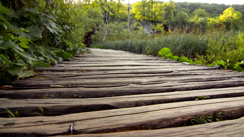 Young woman walking across a wooden bridge in Plitvice National Park, close-up