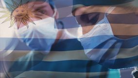 Animation of flag of uruguay waving over surgeons in operating theatre. global medicine, healthcare services during covid 19 pandemic concept digitally generated video.