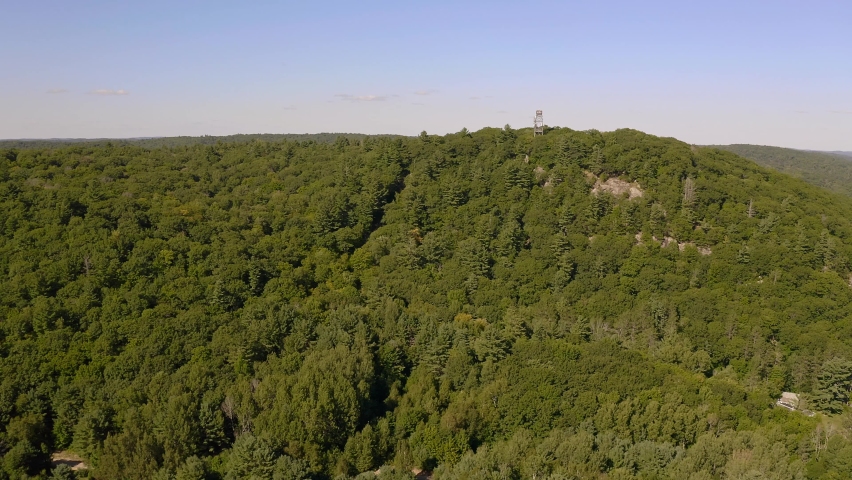 Drone shot approaching lookout tower on hilltop in the middle of Ontario forest