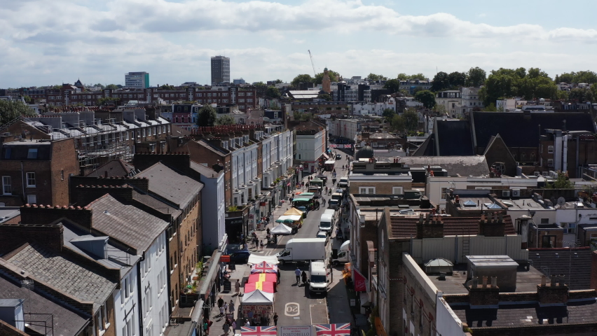 Ascending shot of street market on Portobello Road. Aerial view of street with stands offering various products. London, UK
