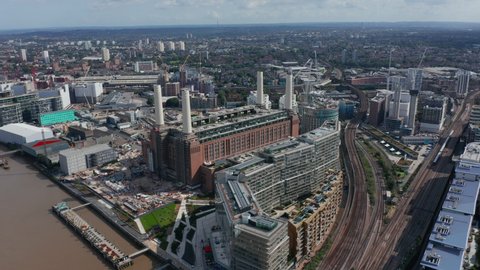 Slide and pan footage of Battersea Power Station complex. Historical coal burning power station with four chimneys on bank of Thames river. London, UK