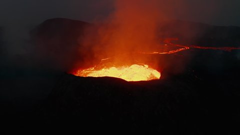 Orbit shot around volcano crater eruption. Close-up of boiling magmatic material in crater and flowing lava stream in background. Fagradalsfjall volcano. Iceland, 2021