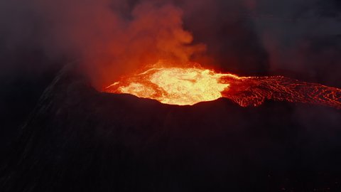 Pull back footage of active volcano. Magma gushing from crater and flowing down in stream. Fagradalsfjall volcano. Iceland, 2021
