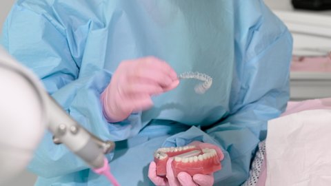 Close up of Orthodontist holding invisible retainer for teeth alignment. In clinic shows patient removable transparent plastic aligners or invisalign use and benefit. High quality 4k footage