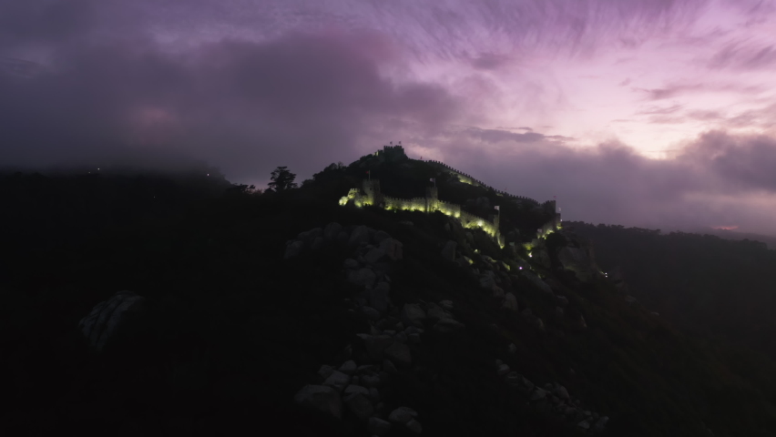 Historic architecture with defensive towers and spectacular views. Aerial footage of purple clouds background and fascinating backlight. Europe, Portugal, Castelo dos Mouros. High quality 4k footage