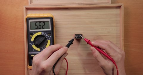Testing 9v battery cell voltage with digital multimeter tool, voltage check showing low power, batty depleted, discharged