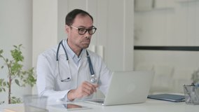 Middle Aged Doctor Talking on Video Call on Laptop in Office 