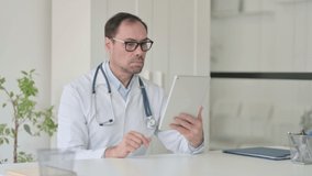 Middle Aged Doctor Talking on Video Call on Tablet in Office 