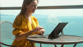 Young Happy Smiling Woman Passes Remote Interview on Internet on Tablet for Employment or in an Educational Institution. Concept of Travel Agent Work from Home, Quarantine, Social Isolation. Sea View