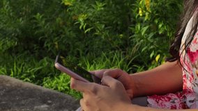 An HD video of a Hispanic girl near plants outdoors texting on her smartphone in Panama