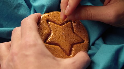 Men's hands scratch brown sugar caramel candy cookies with a metal needle pattern in the form of a star. Close-up of survival game