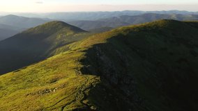 Summer scene of a mountain range illuminated by the sun from a bird's eye view. Location place Carpathian mountains, Ukraine, Europe. Cinematic aerial shot. Beauty of world. Filmed in 4k, drone video.