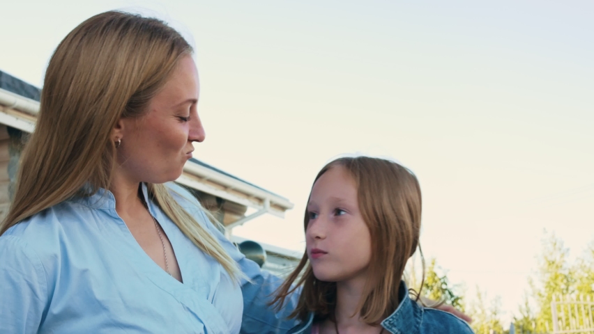 Mom is having fun with the children, the daughter makes faces and shows signs with her fingers. Family fun. Relationship between parents and children. Mom and blond teenage daughter.