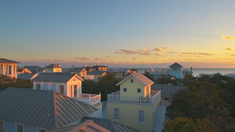 High angle aerial panning view on colorful sunset with sea ocean landscape of Gulf of Mexico in Seaside, Florida from wooden rooftop terrace buildings houses cityscape