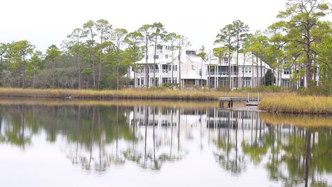 Western lake wetland by Gulf of Mexico in Seaside, Florida on cloudy weather with house reflection pine trees in winter peaceful day
