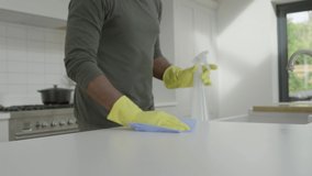Man Cleaning Kitchen Surface with Rubber Gloves and Disinfectant Spray. High quality video