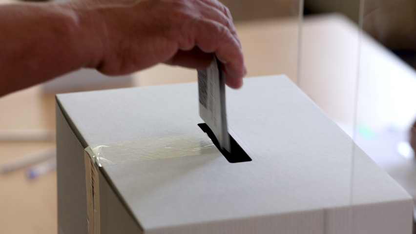 Person casts his vote into a ballot box during elections.