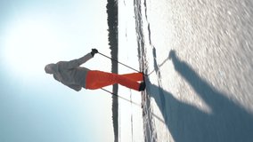 A woman going cross-country skiing on a frozen bay in Finland on a frosty sunny day. Vertical video for smartphone screen, for target social media platforms and web browsers on mobile devices.
