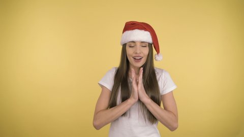 Young attractive woman 35 years old in the Red Hat of Santa Claus. Young lady on yellow background isolated.