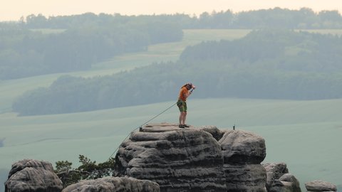 PRACHOV, CZECH RPUBLIC - JUNE 05, 2019: Rock climber arriving to the top of a rock tower at Prachov Rocks, popular outdoor destination in Chesky Raj