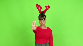 Young woman wearing christmas hat doing stop sign over isolated background. Green screen chroma key