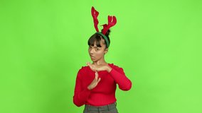 Young woman wearing christmas hat doing time out gesture over isolated background. Green screen chroma key
