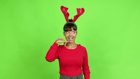 Young woman wearing christmas hat making phone gesture and speaking with someone. Call me back sign over isolated background. Green screen chroma key