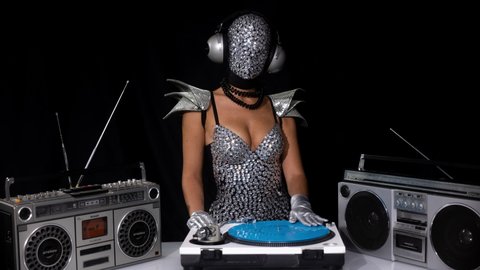 Mrs disco woman with a shiny mirror effect face wearing headphones and Djing on turntables