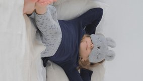 Vertical Video. Cute Little Girl Lounging in her Bed, Chilling at Home. Happy Childhood Concept