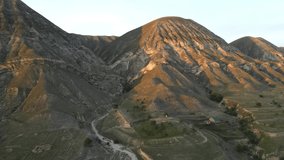 Mountain peaks in the rays of the setting sun, aerial view, drone video, camera rotation. Geology, layers of rocky mountains and hills. Nature background. Hiking, rock climbing. Russia Dagestan.