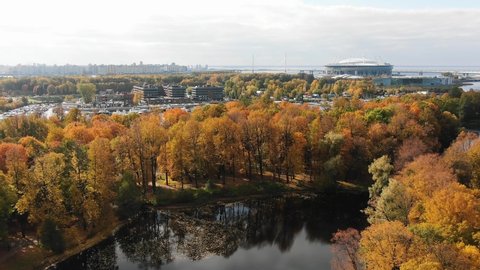 Aerial view of the autumn city park with bright yellow trees and a modern stadium in St. Petersburg on a sunny autumn day