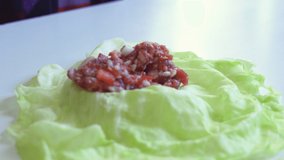 Woman prepares cabbage rolls. Close-up 4k video of housewife cooking tasty stuffed cabbages with minced meat. Home cooking process of healthy food. Preparing stuffed cabbage rolls
