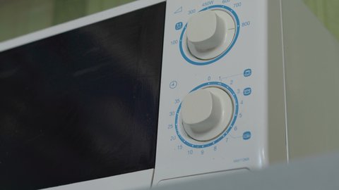 Close-up shot of a person cleaning a microwave with vinegar. Housewife hand in rubber gloves cleans microwave oven. Old microwave cleaning