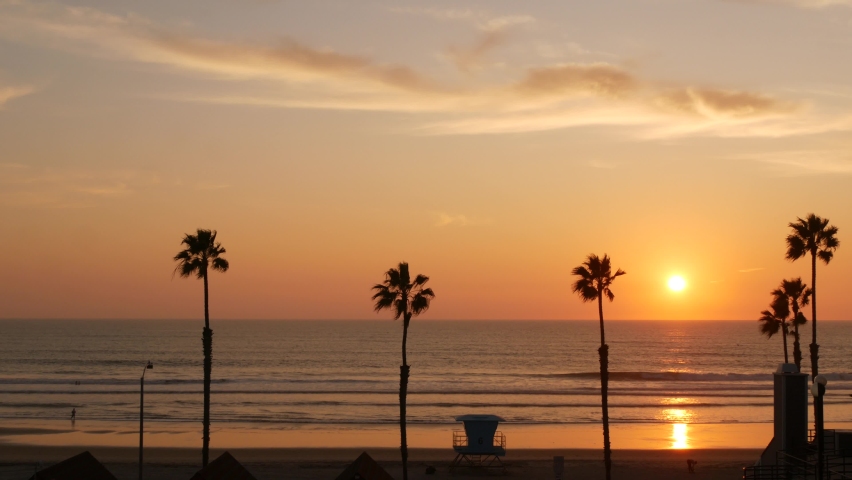 Palms silhouette sunset sky, California aesthetic. Oceanside USA. Tropical pacific ocean beach atmosphere. Dark black palm tree, Los Angeles vibes. Lifeguard watchtower, baywatch watch tower hut.