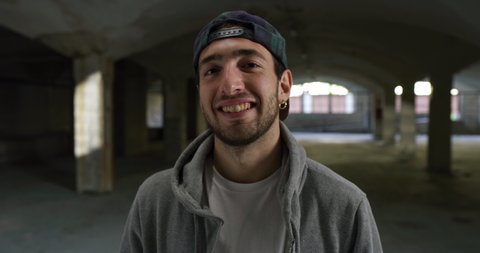 Cinematic shot of young happy arab guy smiling in camera satisfied with his training results of freestyle soccer in public underground parking.