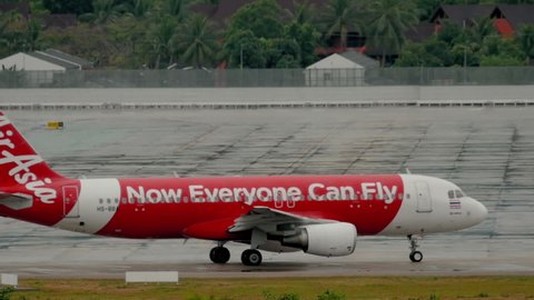 PHUKET, THAILAND - DECEMBER 2, 2016: Low-cost airline Airbus 320 of AirAsia taxiing at runway before departure on wet runway of Phuket airport (HKT). Rainy weather