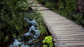 Young hiker in shorts walking along a wooden bridge in Plitvice National Park