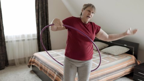 Belly exercise with hula hoop, Overweight female in red t shirt twirling hula hoop, Fatty woman exercise for weight loss, slimming process. Slow motion.