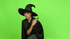 Young woman wearing witch hat for halloween parties with shoulder pain over isolated background. Green screen chroma key