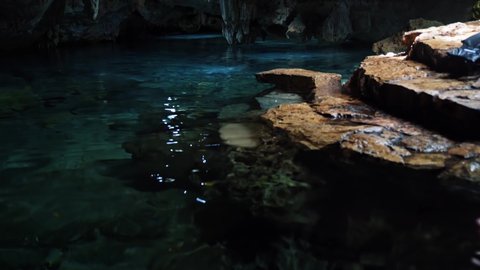 Tilt up shot of a beautiful underground Mexican Cenote with Stalactites growing from the roof and crystal clear blue fresh water in a eco-park Kantun Chi on Playa del Carmen in Riviera Maya, Mexico