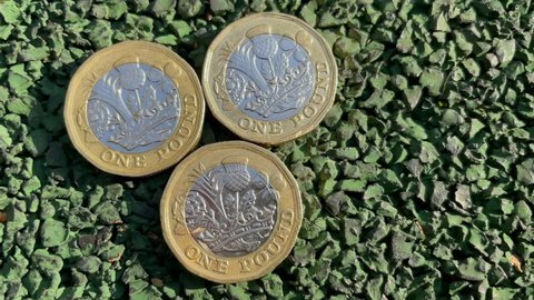 4k Video British Pound Sterling Coins closeup. Pound Coins laying on the road on the sunlight. Three one pound coins. Stability concept. British metal money.