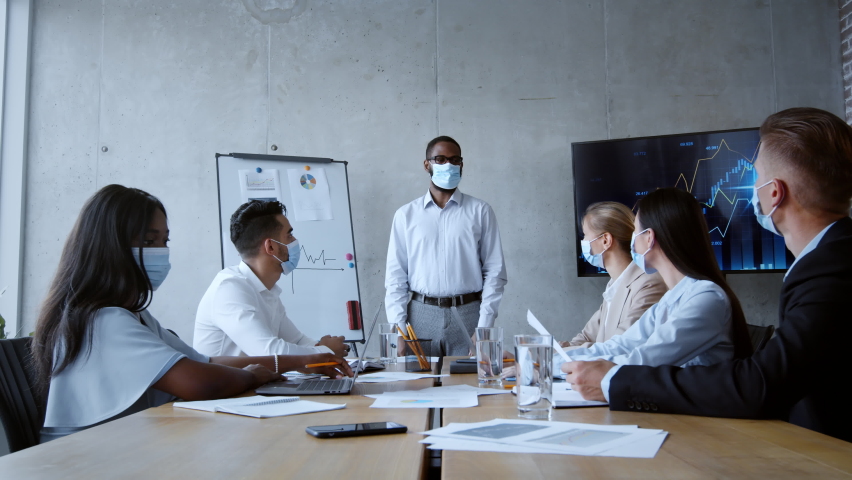Corporate lifestyle. Multiethnic diverse business team discussing marketing strategy during offline meeting, african american boss talking to manager, everyone wearing face masks, zoom in, slow motion | Shutterstock HD Video #1080181964