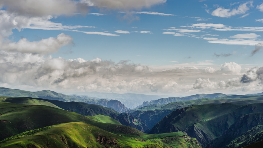 Alpine meadows. Play of light and shadows. Mountain meadow. 4k Time-Lapse. Beautiful movement of clouds on a sunny day.  The sun rays and cloud shadows on the mountainous terrain. Tonal perspective