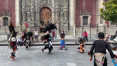 Mexico City, Mexico - October 3, 2021: People wearing ornaments and body paint representing the Aztec Mexica ethnic group performs in front of the Metropolitan cathedral, historic center of CDMX.
