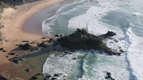 Ocean aerial with mountains meet the Atlantic waves. Spectacular views and scenery of the sandy beach with rocky islet along. Europe, Portugal, Cordoama Viewpoint. High quality 4k footage