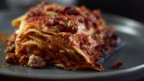 Close up of a fork cutting a beautiful piece of a sumptuous traditional Italian lasagna