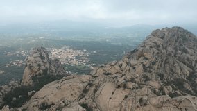 View from above, drone point of view, stunning aerial video of a drone flying over a granite mountain range during a cloudy day. San Pantaleo village in the distance, Sardinia, Italy.